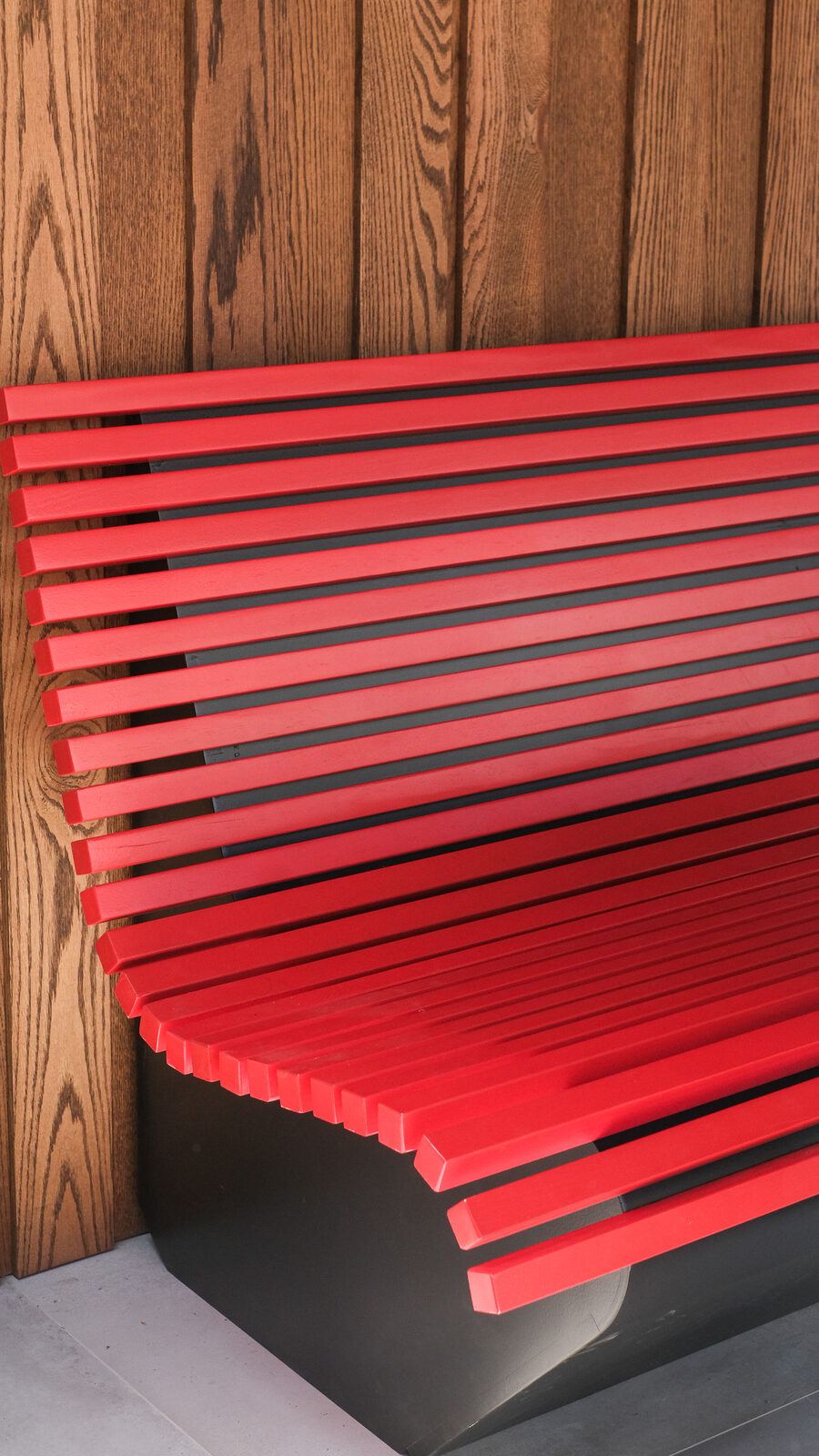 Red slatted bench curving up into a backrest, ULU